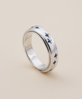 Silver ring with blue accents on a beige background