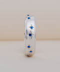 Silver ring with star-shaped blue gemstones on a beige background