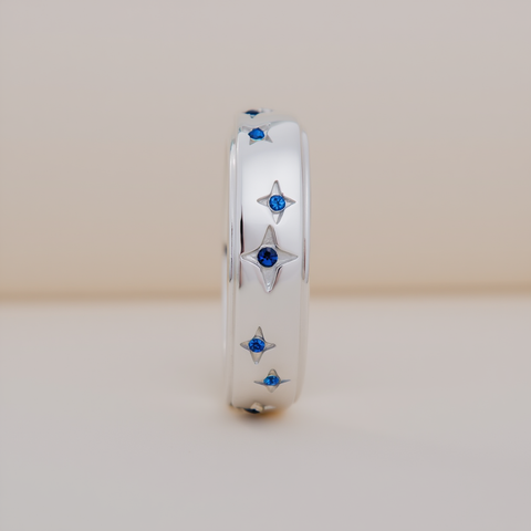 Silver ring with star-shaped blue gemstones on a beige background