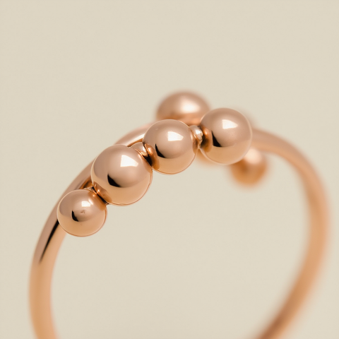 Rose gold ring with five beads on a beige background