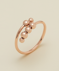Rose gold ring with spherical beads on a beige background