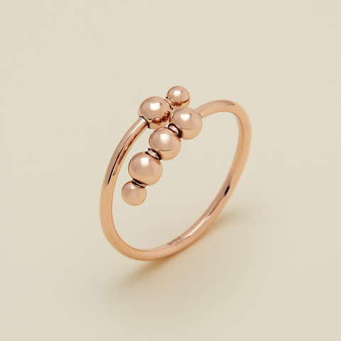 Rose gold ring with spherical beads on a beige background
