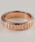 Rose gold ring with textured design on a light gray background