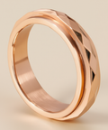 Rose gold faceted spinner anxiety ring on a beige neutral background 