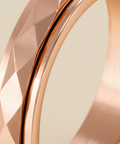 Close-up of a rose gold ring with geometric design on a beige background