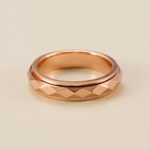 Rose gold ring with textured design on a beige background