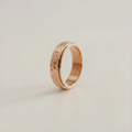Rose gold ring with a textured surface on a light beige background