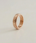 Rose gold ring with a textured surface on a light beige background