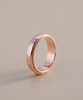 Rose gold ring with embedded diamonds on a beige background