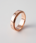 Rose gold ring with embedded diamonds on a light gray background