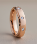 Rose gold ring with embedded diamonds on a neutral background