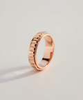 Rose gold ring with a textured design on a light gray background