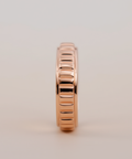 Rose gold ring with a textured design on a beige background