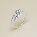 Silver ring with three spherical beads on a beige background