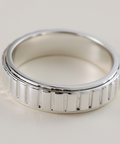 Silver ring with a textured band on a light background