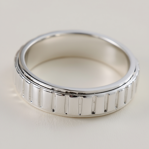 Silver ring with a textured band on a light background