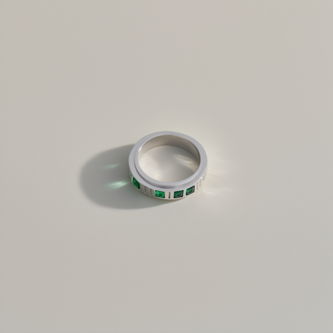 Silver ring with green gemstones on a light gray background