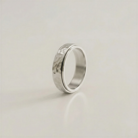 Silver ring with a textured surface on a light beige background