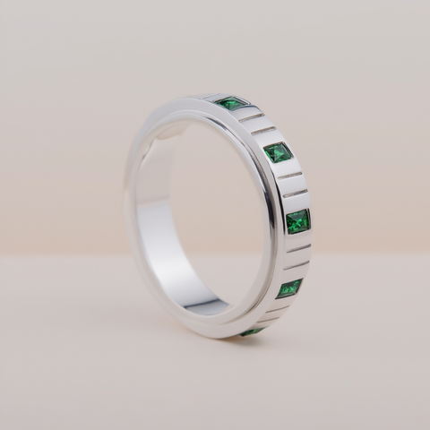 Silver ring with green gemstones on a light beige background