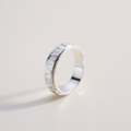 Silver ring with a textured band on a light gray background