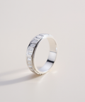Silver ring with a textured band on a light gray background