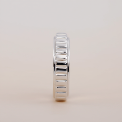 Silver ring with a textured band on a light beige background