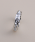Silver ring with embedded diamonds on a light gray background