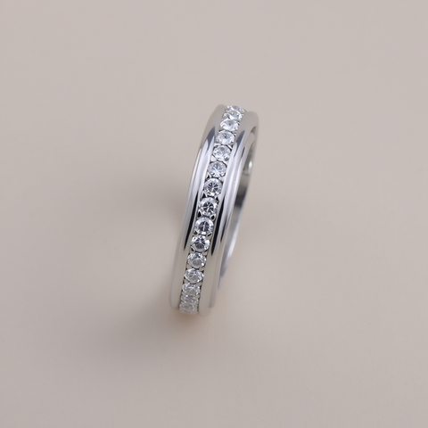 Silver ring with embedded diamonds on a light gray background
