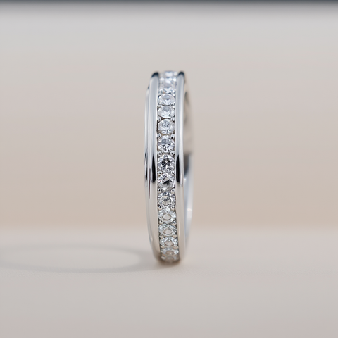 Silver ring with small diamonds on a light gray background