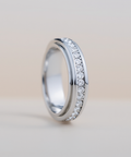 Silver ring with small diamonds on a light beige background