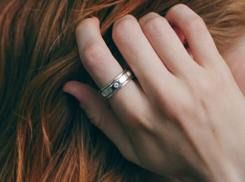 Hand wearing a silver ring with a diamond on a fur background