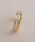Gold ring with embedded diamonds on a beige background