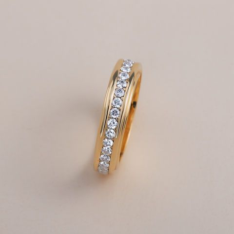 Gold ring with embedded diamonds on a beige background