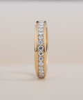 Gold ring with embedded diamonds on a light beige background