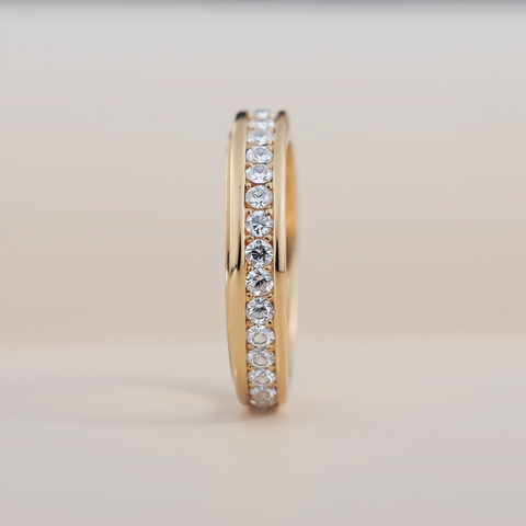 Gold ring with embedded diamonds on a light beige background