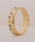 Gold ring with blue gemstones on a light background