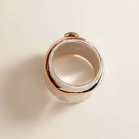 Silver ring with rose gold band on a beige background
