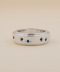 Silver ring with small blue stones on a beige background