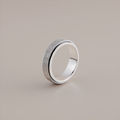 Silver ring with textured surface on a beige background