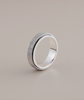 Silver ring with textured surface on a beige background