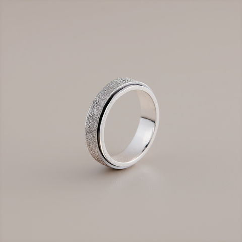 Silver ring with textured surface on a beige background