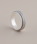 Silver ring with textured band on a beige background