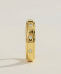 Gold ring with diamond accents on a light beige background