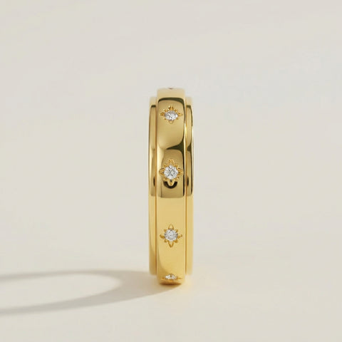 Gold ring with diamond accents on a light beige background