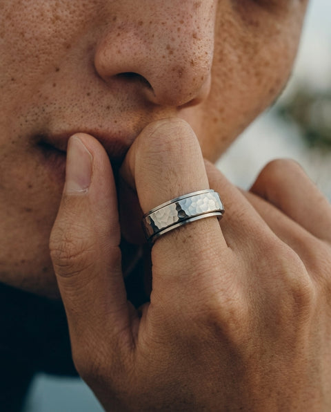 Close-up of a person's hand with a silver ring on a blurred background