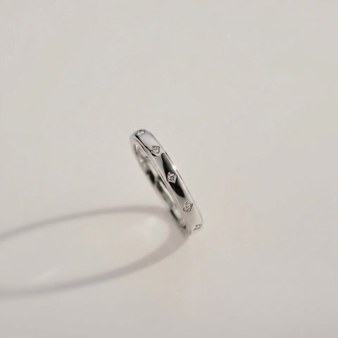 Silver ring with small diamonds on a light gray background