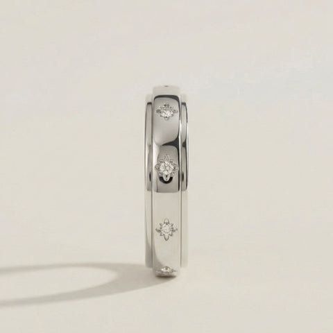 Silver ring with diamond accents on a light gray background