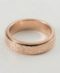 Rose gold ring with a textured band on a light gray background