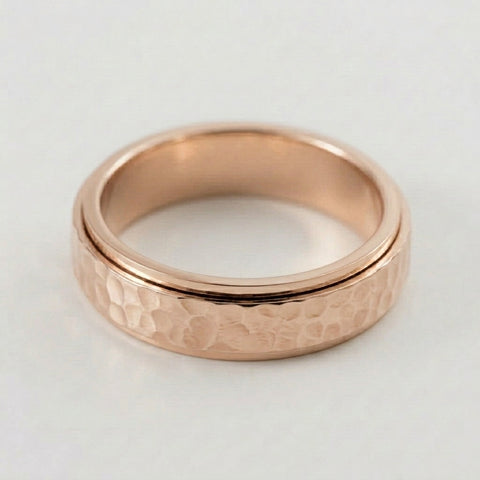 Rose gold ring with a textured band on a light gray background