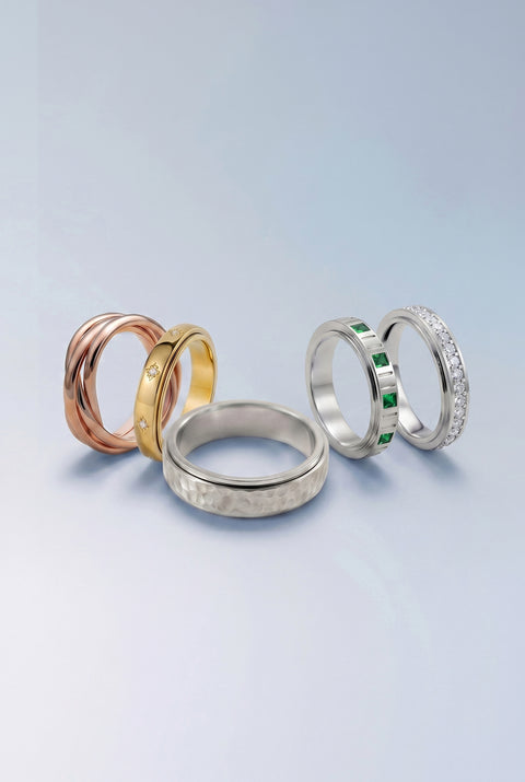 Four rings in different colors and designs on a light gray background